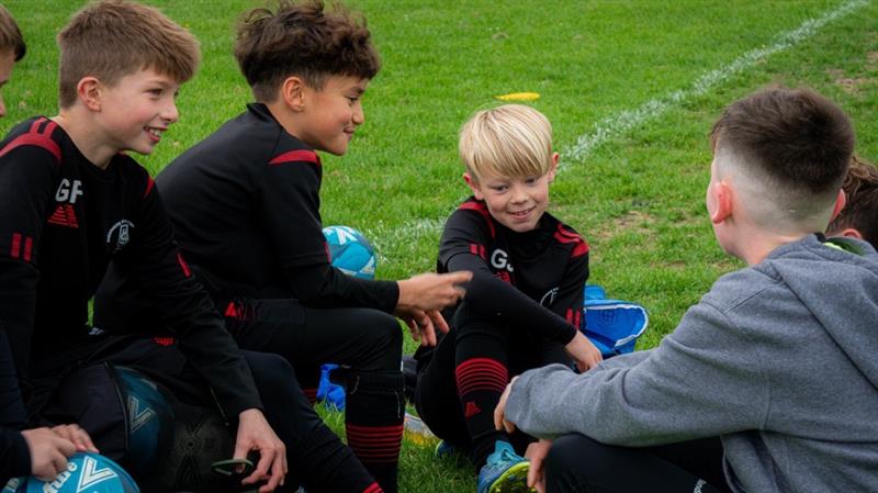 Sheerness East Youth Football Club players sitting on the pitch together